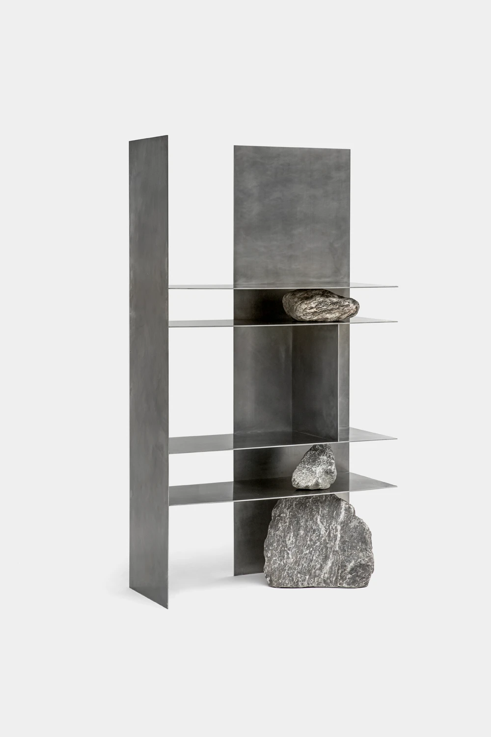 A shelving unit made of folded sheet metal, with natural stones integrated as structural supports for the shelves.